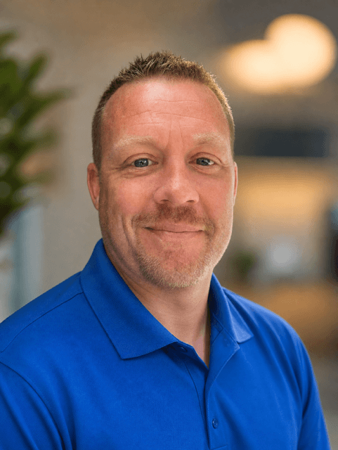 Smiling middle-aged man with short spiky hair and a goatee wearing a blue polo shirt.