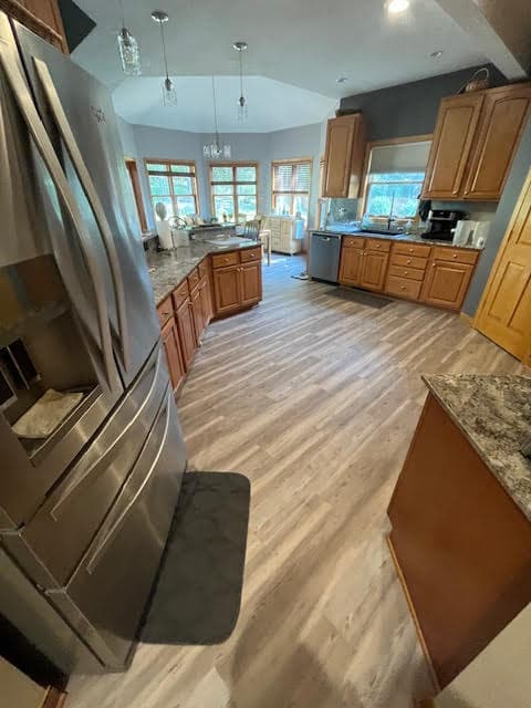 Spacious kitchen featuring oak cabinets, stainless steel refrigerator, and light wood-look flooring throughout the room.