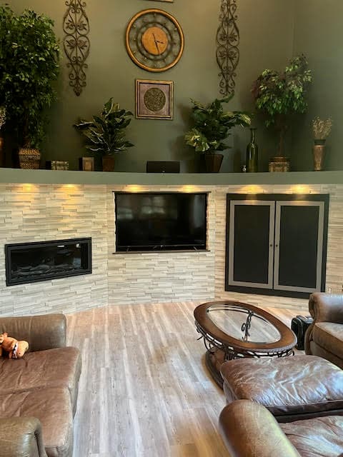 Cozy living room with a stone-textured wall, built-in fireplace, TV, and brown leather seating.
